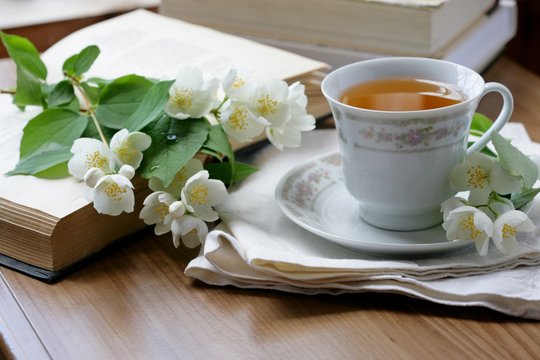 Cup of green tea with a books and jasmine. Selective focus.