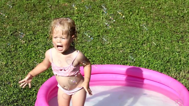 A girl playing in a water-filled kiddie pool