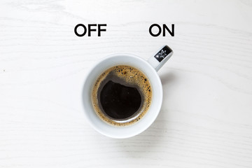 Cup of coffee on white desk, switched on, concept