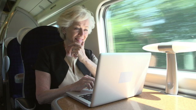 Businesswoman Commuting To Work On Train And Using Laptop
