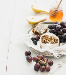Camembert cheese with grape, walnuts, pear and honey on vintage