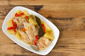 fish stew on white dish on brown wooden background