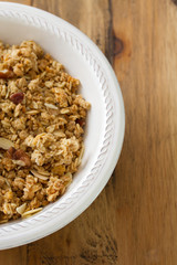 granola in white bowl on brown wooden background
