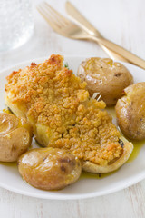 fried cod with bread and potato on dish on white wooden background