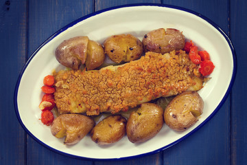 fried cod with corn bread and potato on dish on blue wooden background