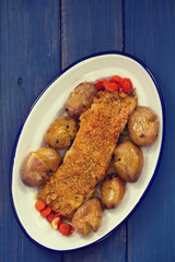 fried cod with bread and potato on dish on blue wooden background