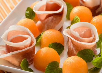 Palline di melone con roselline di prosciutto crudo, closeup, fuoco selettivo