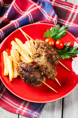 Barbecued kofta with fries on a plate