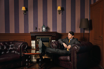 Businessman relaxing while sitting in a leather executive chair.