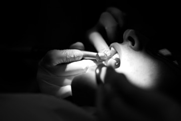 Dentist hands holding a drill towards patient teeth - obrazy, fototapety, plakaty