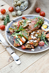 Many delicious bruschetta with cheese, tomato, quail egg, ham