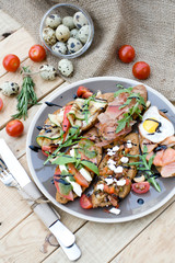 Many delicious bruschetta with cheese, tomato, quail egg, ham
