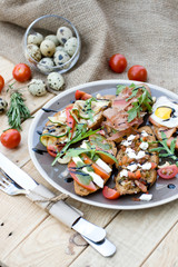 Many delicious bruschetta with cheese, tomato, quail egg, ham