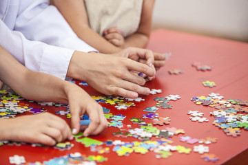 Children, friends hands assemble the puzzle on the table color