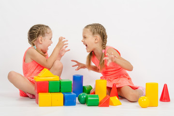 Two girls frighten each other by playing with blocks