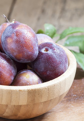 Delicious blue plums in a wooden bowl, selective focus