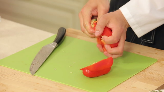 Cheff is Slicing Red Paprika on a Cutting Board
