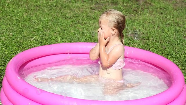 A girl playing in a water-filled kiddie pool
