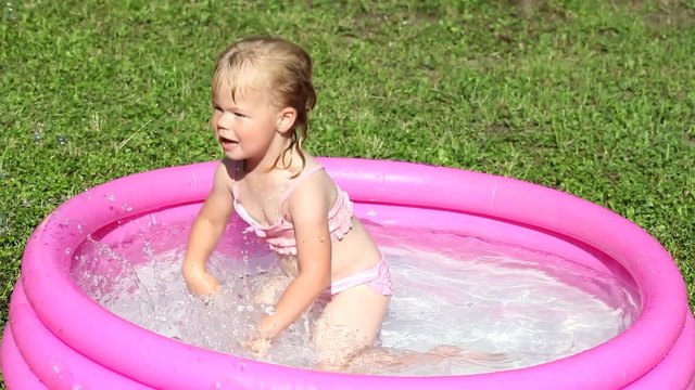 A girl playing in a water-filled kiddie pool