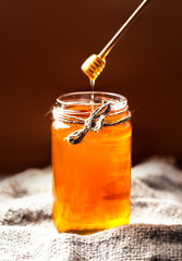 Fresh Honey in jar with honey dipper on vintage wooden backgroun