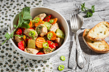 meat stew with vegetables - carrots, onions and sweet peppers in a white bowl on a light wooden background