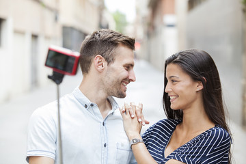 cheerful young couple making a selfie with a smartphone and selfie stick
