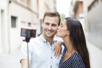 cheerful young couple making a selfie with a smartphone and selfie stick