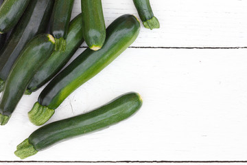 Pile of whole courgettes from above on white weathered wood.