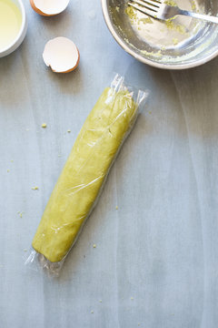 Green sablee pastry with matcha powder wraped in plastic film for chilling
