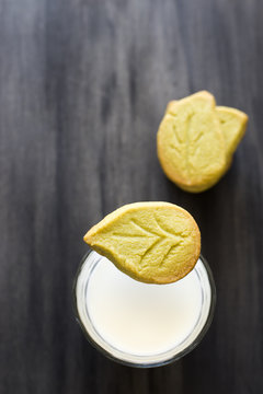 Light snack of homemade leaf-shaped green tea cookies and a glass of milk. Selective focus.