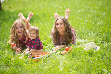 Obraz na płótnie Canvas Beautiful girls with little boy on the grass