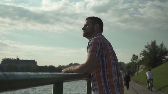 Pensive man standing near the river
