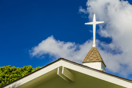 The steeple and cross on the roof of a small chapel