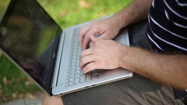 Businessman with a laptop sitting in a park
