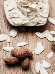 sliced and whole raw almonds on wooden surface