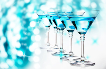 Blue cocktails in martini glasses on bright background