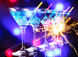 Blue cocktail in martini glasses on bright background