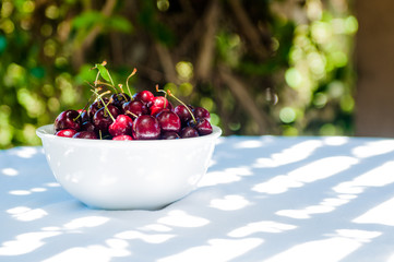 white bowl of cherries outside