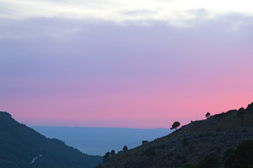 Scenic sunset in the mountains. The pink and grey colors of sunset in the mountain valley in rural Spain near Valencia.