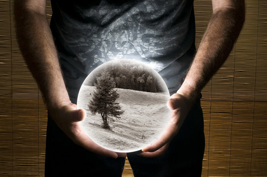 Man Holding White Sphere with Sepia Landscape Picture Inside