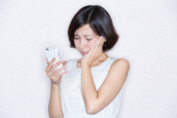 スマホを見て悲しむ女性