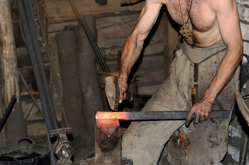 Blacksmith working on metal on anvil at forge high speed