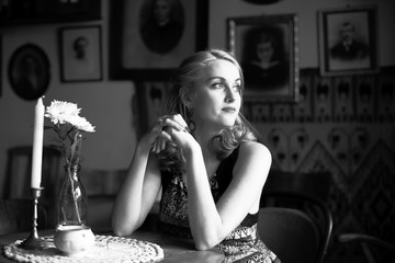 Beautiful young lady sitting at a table, a black-and-white portrait in retro style.
