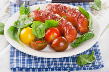 Fried sausages with fresh salad on white plate.
