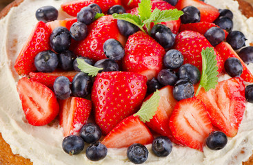 Strawberry and blueberry  cream cake on  wooden background.