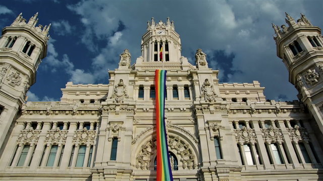 Low angle view of rainbow flag in City Council of Madrid against cloudy sky