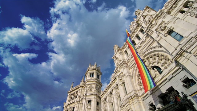 Rainbow flag in Madrid city hall with blue sky and clouds