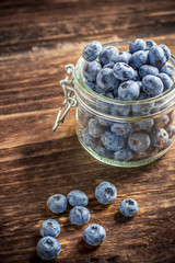 Gardening blueberries in a simple rustic bowl on dark wooden background