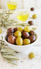 black and green olives, olive oil on a white wooden table