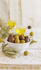 black and green olives, olive oil on a white wooden table